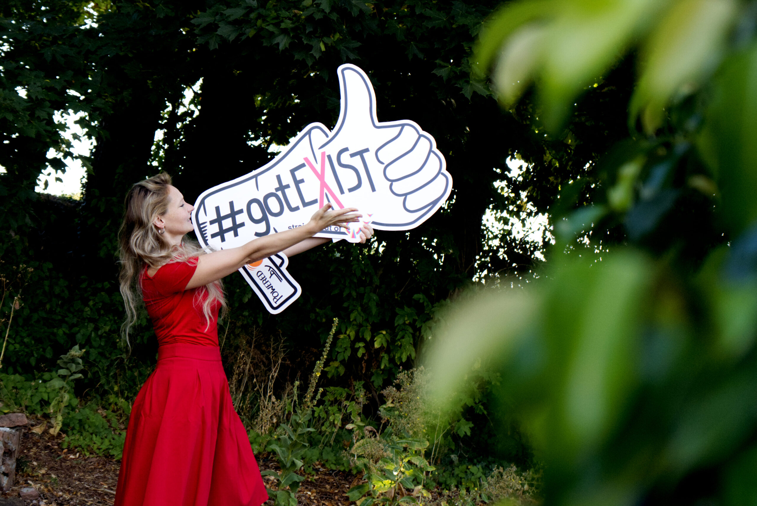 Frau mit „#gotEXIST“-Schild in der Natur